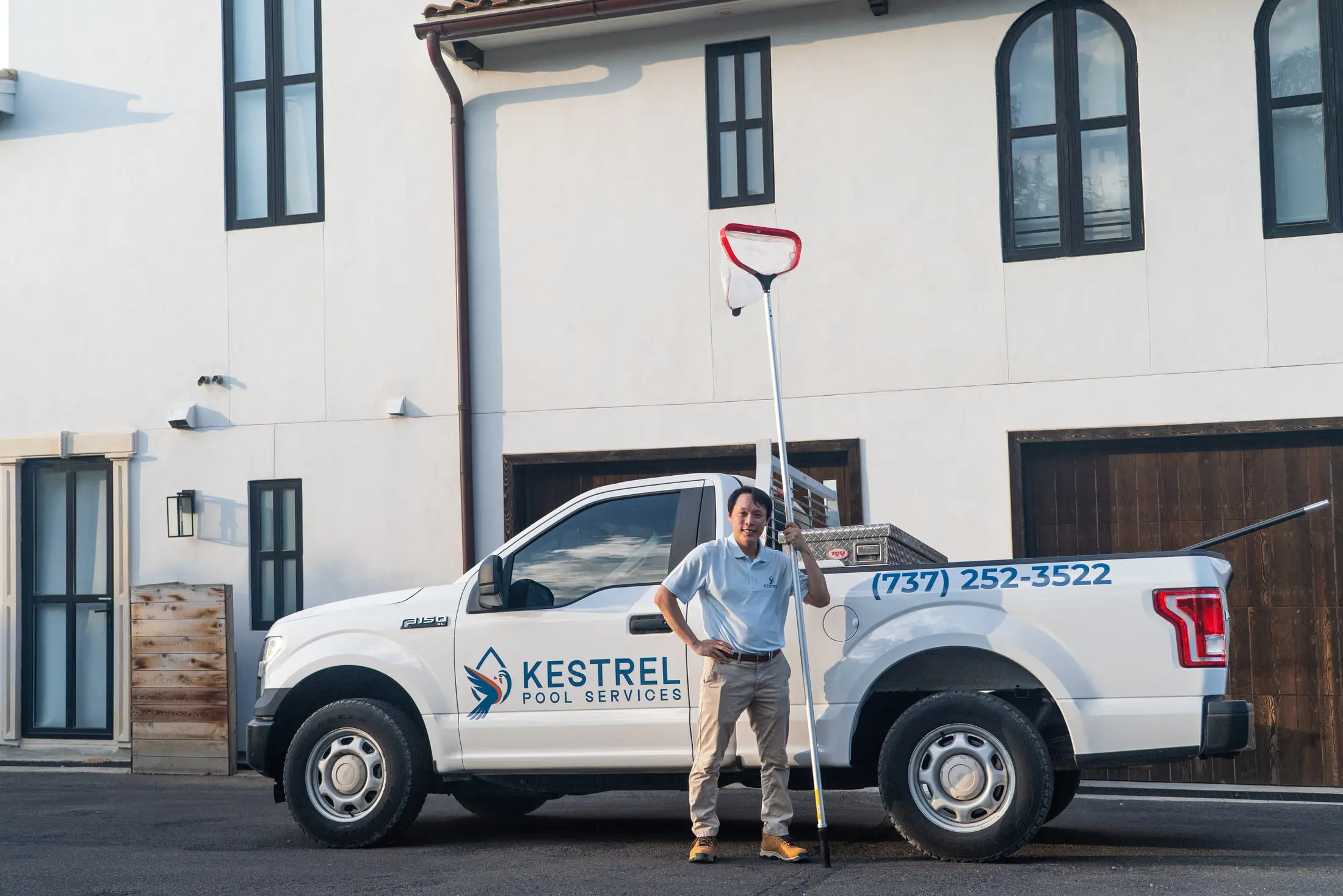 Ji standing with a pool pole beside the Kestrel Pool Services truck